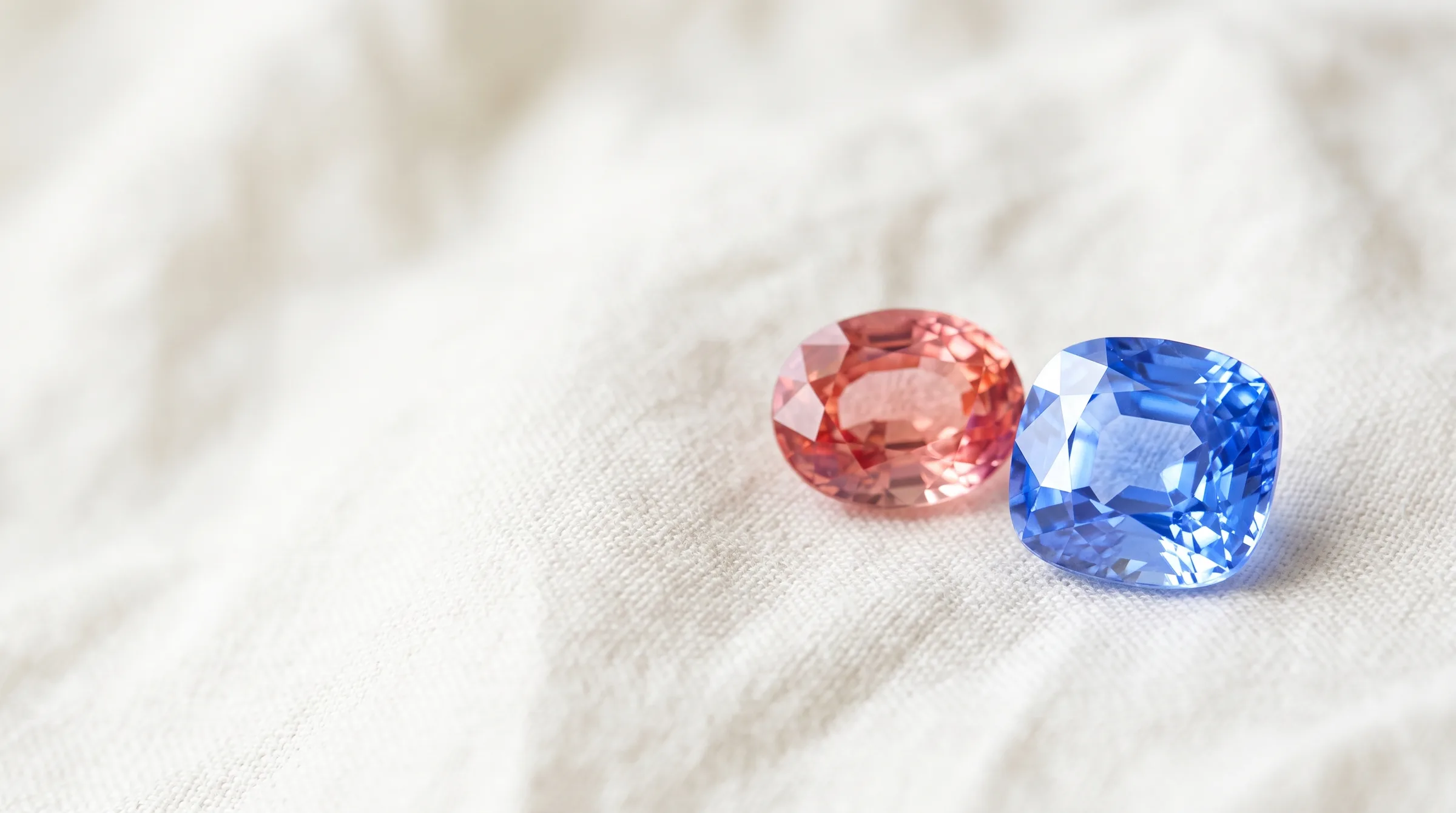 A padparadscha and a blue Ceylon sapphire on white linen - Crestonne
